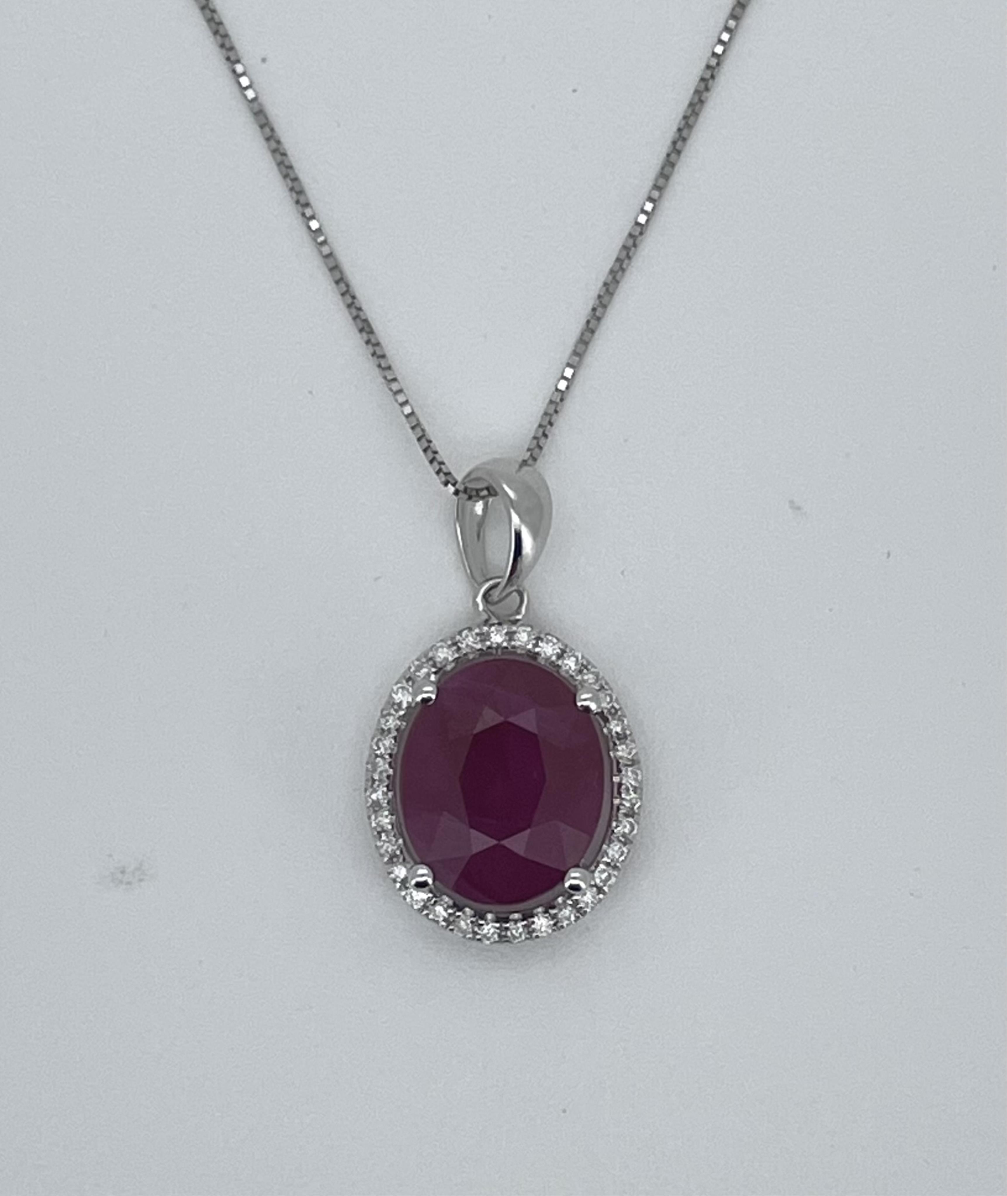 A modern 750 white metal, ruby and diamond cluster set oval pendant, overall 12mm, on a 750 white metal chain, 42cm, gross weight 3.1 grams.